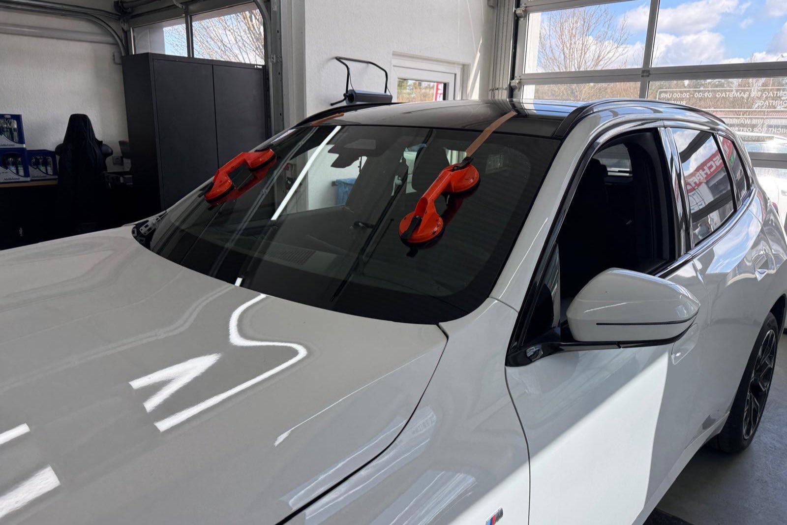 Neue Windschutzscheibe wird mit Saugnäpfen in einen BMW X3 eingesetzt – Werkstatt des Fränkischen Autoglas Zentrums